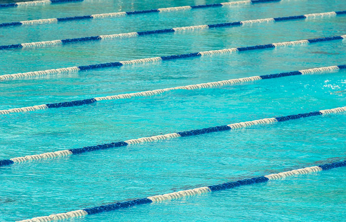 View of an Olympic swimming pool featuring floating lane dividers in calm water.