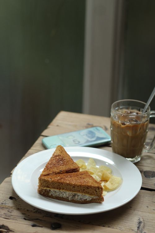 Free A rustic wooden table with iced coffee, sandwich, and potato chips, perfect for lunch. Stock Photo