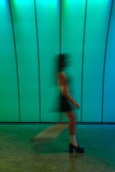 Artistic shot of a woman walking through a colorful tunnel with blurred motion.