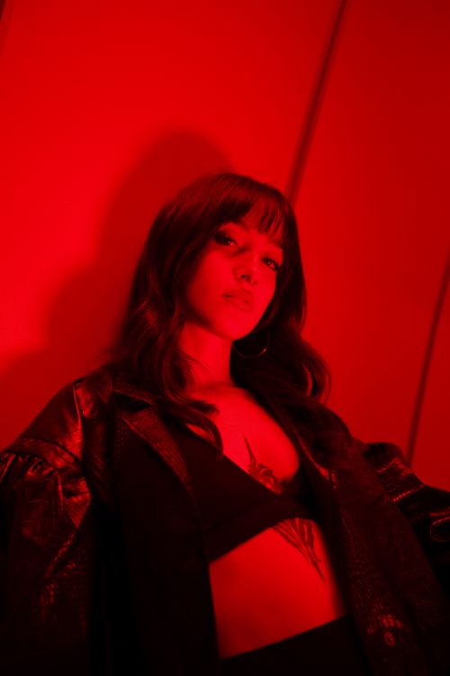 Free Sultry portrait of a woman in a black leather jacket under red lighting. Stock Photo