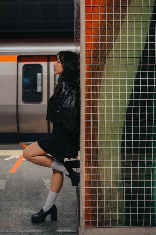 Young Woman in a Black Short Jacket and Mini Skirt on the Subway Platform