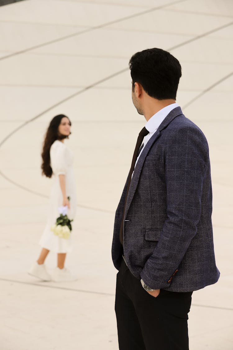 Well-dressed Man Looking Back Over Shoulder On Woman In White Dress