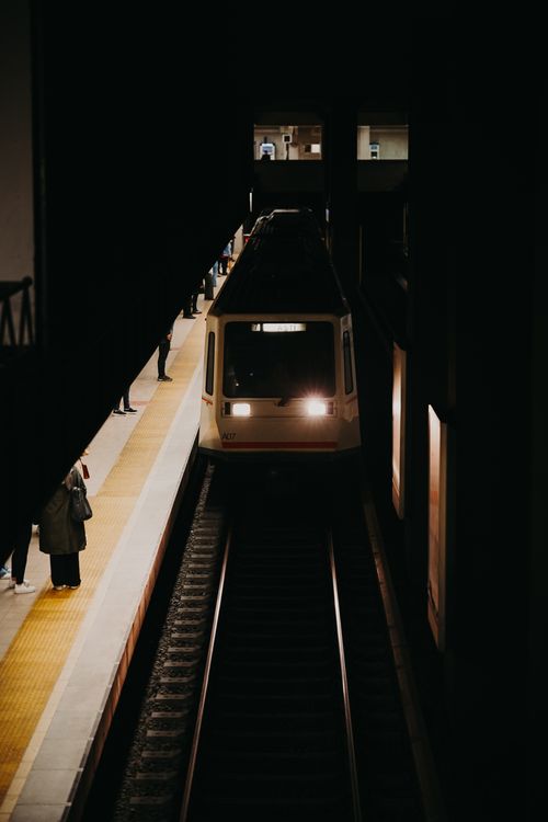 Free Dimly lit metro train arriving at an Ankara subway station platform with passengers waiting. Stock Photo