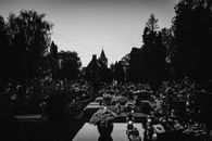 A solemn black and white landscape of a cemetery at dusk with tombstones and trees.
