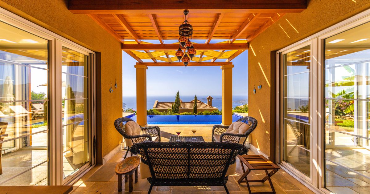Covered terrace with wicker seating, infinity pool, tiled floor and sea view