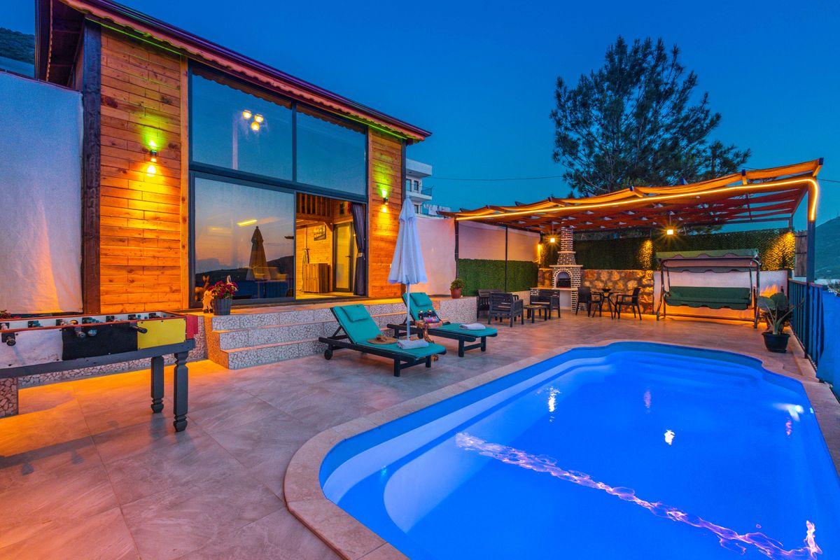 À noite, a piscina perde calor pela superfície Piscina residencial com espreguiçadeiras no pátio ao anoitecer