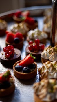 Close-up of assorted mini tartlets topped with fresh berries and meringue.