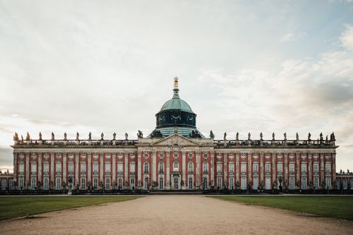 Free Front view of the New Palace in Potsdam, showcasing baroque architecture under a cloudy sky. Stock Photo