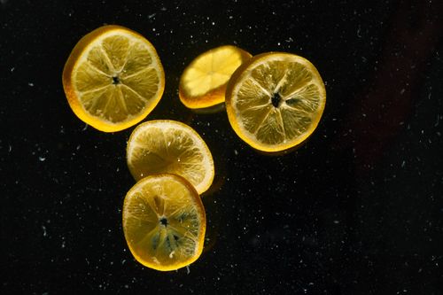 Free Several lemon slices float against a dark water background, highlighting their vibrant color and juicy texture. Stock Photo