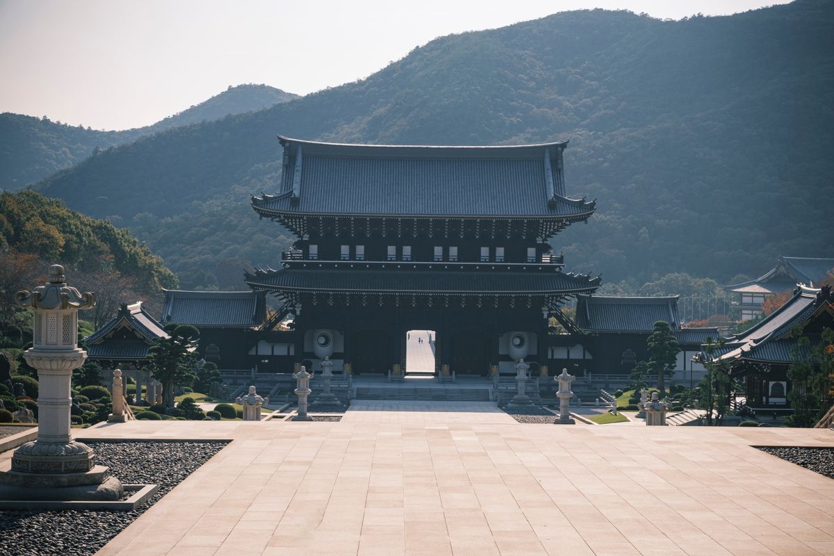 Beautiful Japanese temple at the foothills of forested mountains, evoking the wooded hillside setting of Chuson-ji in Hiraizumi