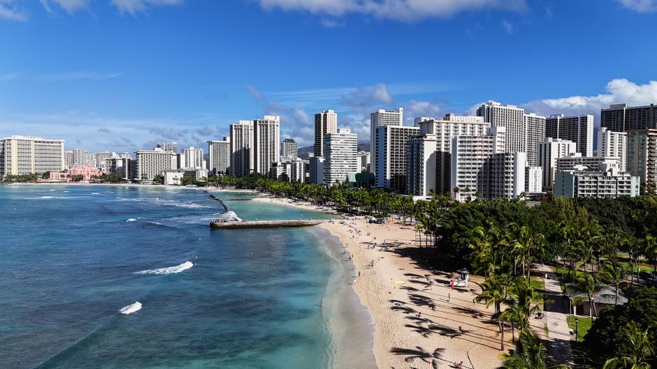 Photo by David Yu Discover the stunning skyline and beachside views of Honolulu's Waikiki Beach.