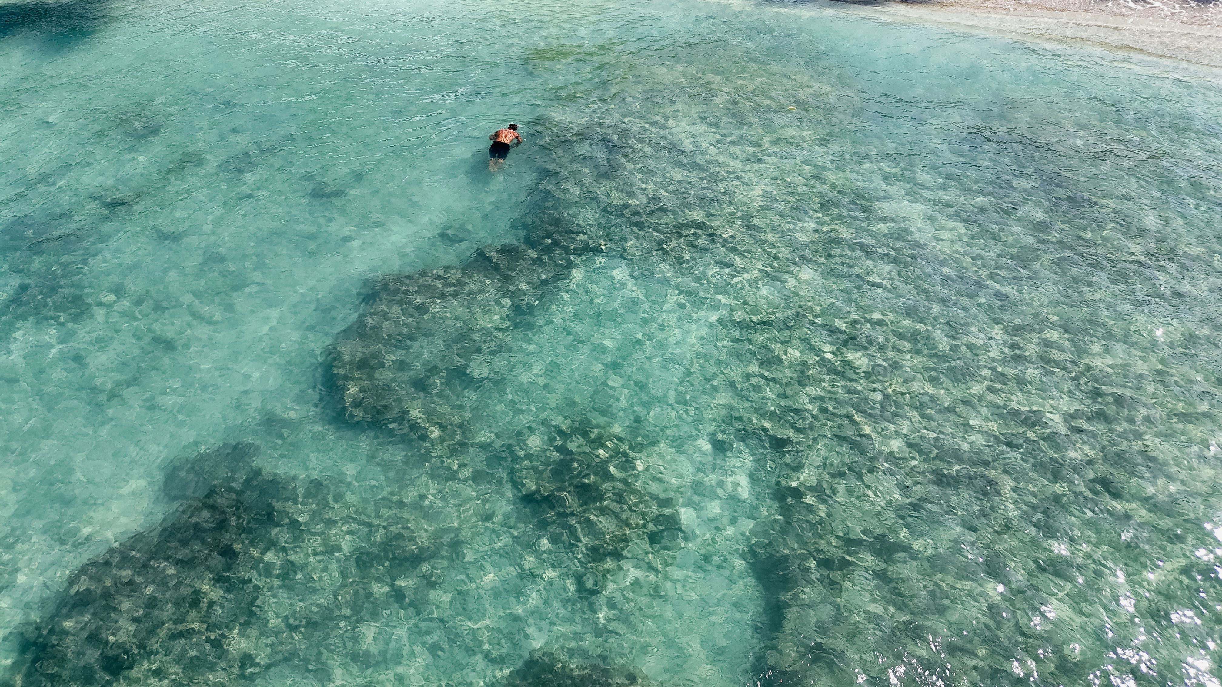 A tranquil aerial view of a swimmer enjoying clear ocean water.