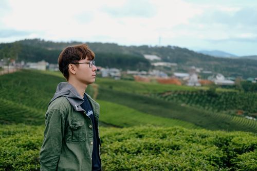 Free Profile of a young man wearing glasses amidst rolling vineyards and lush greenery. Stock Photo