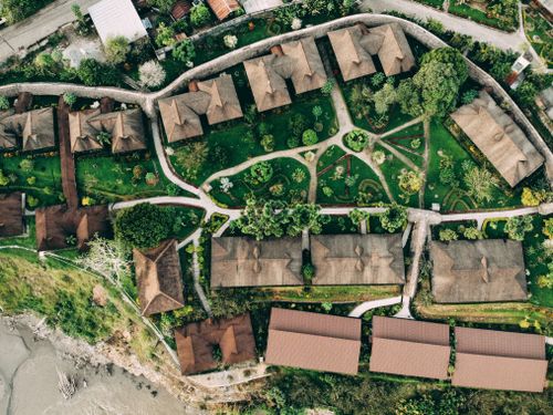 Free A drone-captured aerial view of a picturesque village with lush gardens and traditional houses. Stock Photo