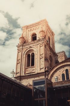 A majestic view of a historic church tower with intricate architecture under cloudy skies.