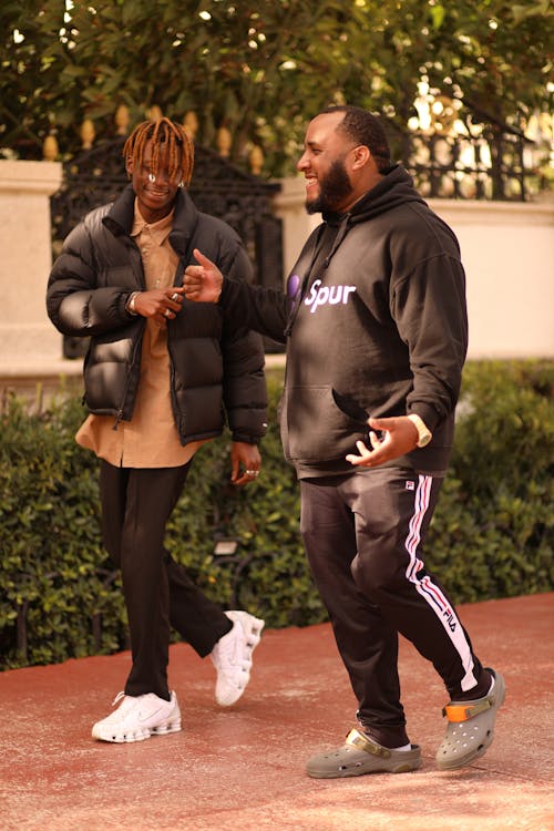 Two men in black jackets and sneakers walking