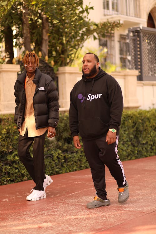 Two men walking down a sidewalk in front of a building