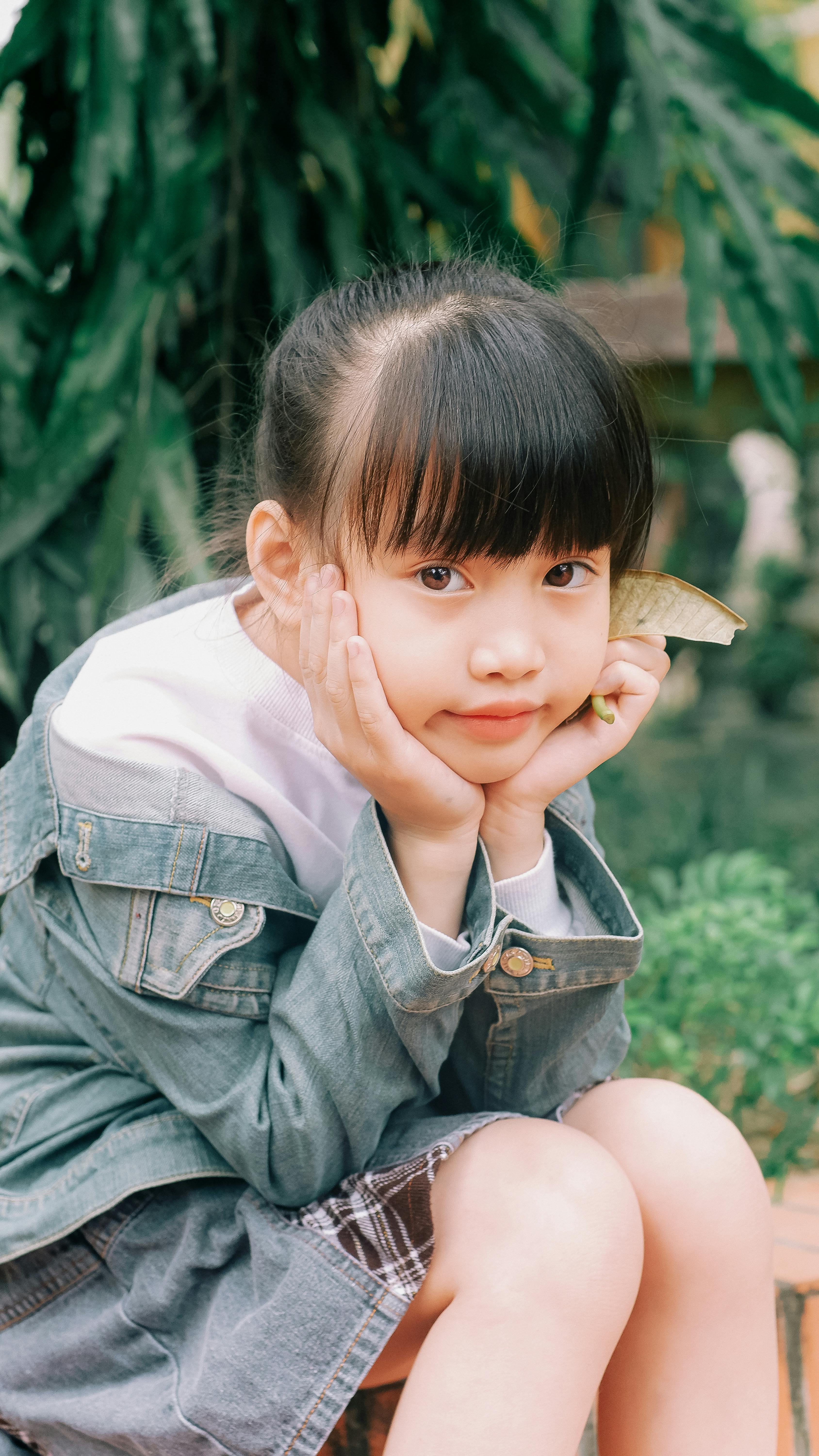 Charming portrait of a young girl sitting in a lush garden, embodying innocence and nature.