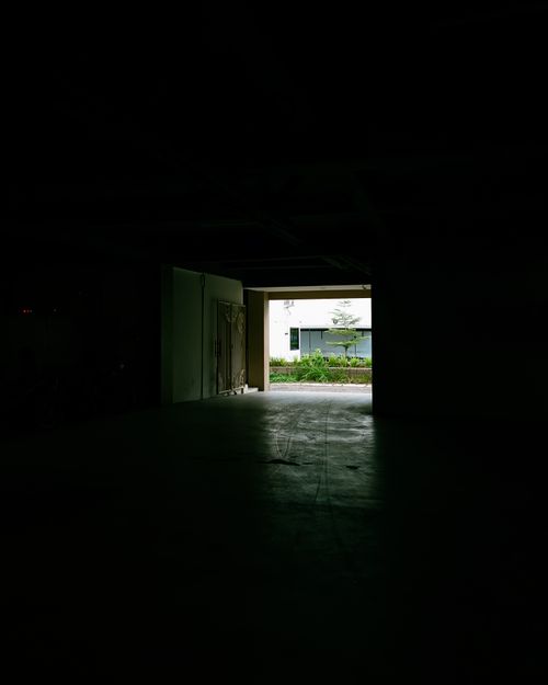 Free Dark corridor leading to a sunlit outdoor area, creating a dramatic contrast. Stock Photo