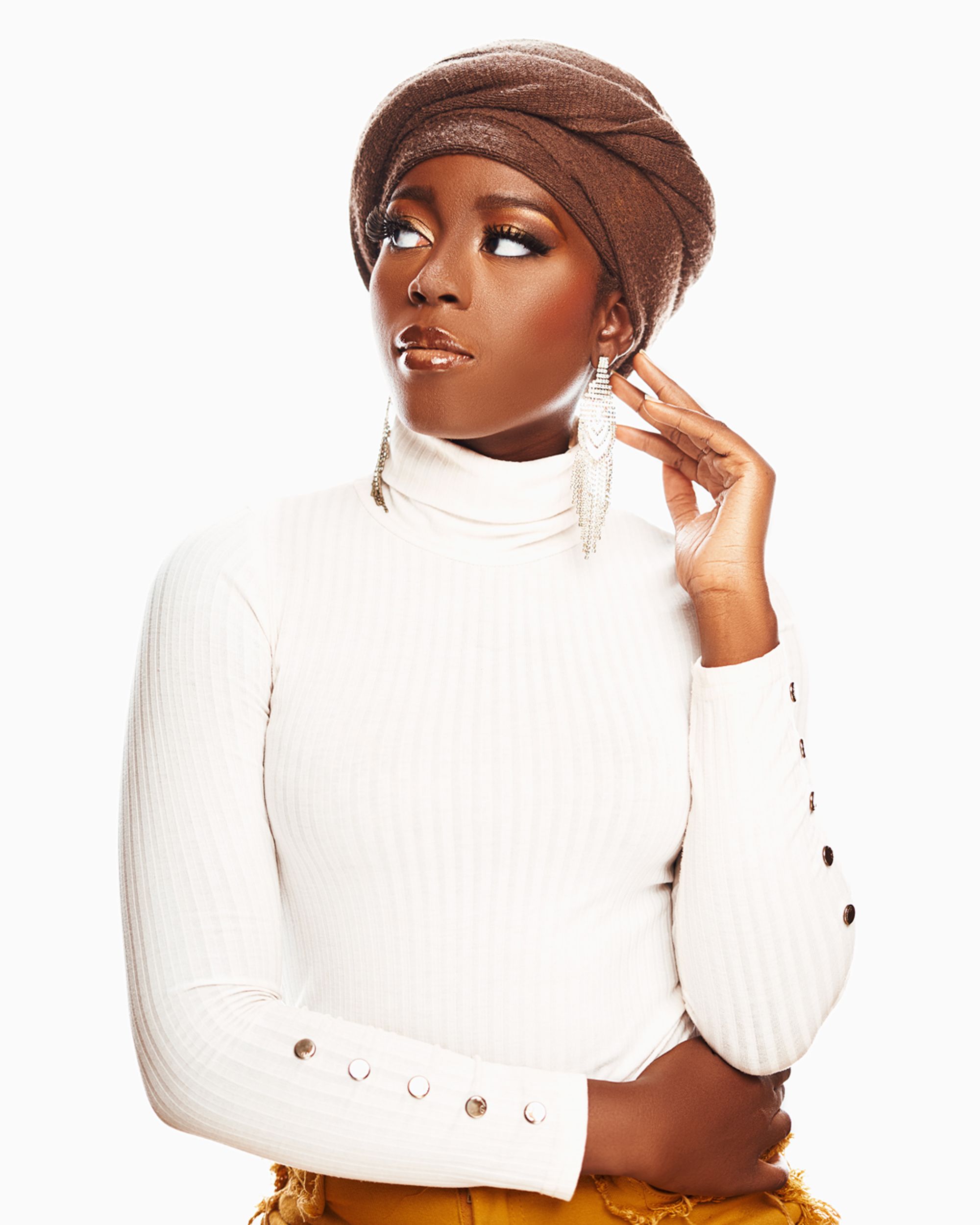 Elegant black woman wearing a white turtleneck and a stylish brown hat in a studio setting.