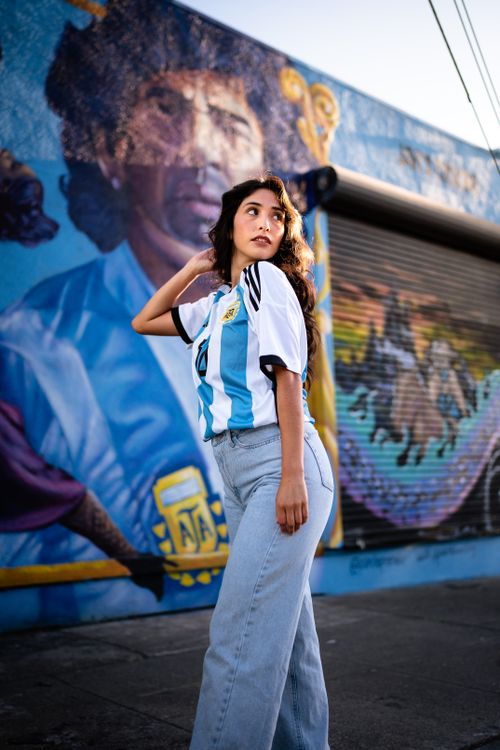 Free Woman in football jersey posing by a colorful mural on a city street. Stock Photo