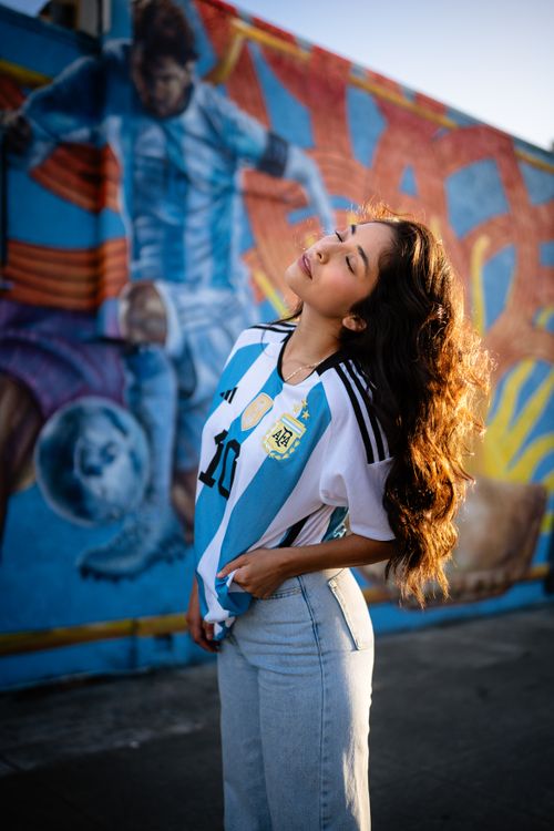 Free Fashionable woman poses in front of a colorful soccer mural, outdoors in daylight. Stock Photo