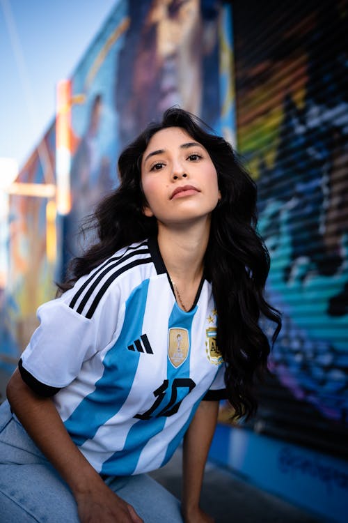 Brunette Woman in Argentinian Football Shirt against Mural