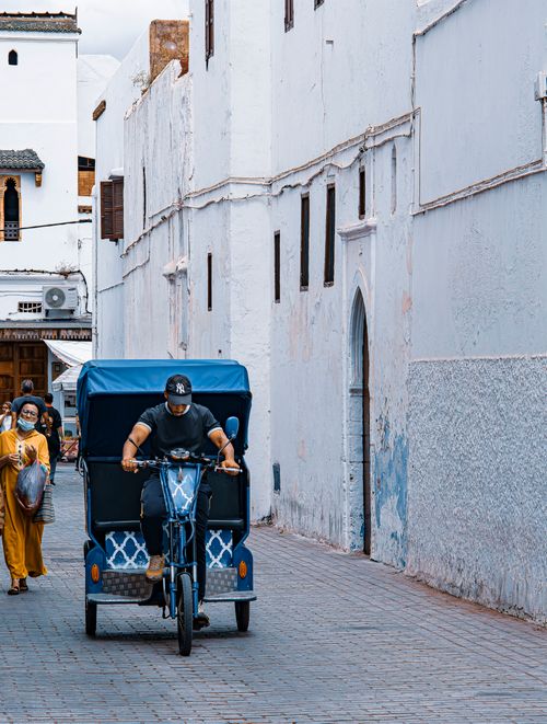 Free A person rides a bicycle carriage on a narrow street in an urban setting, displaying local culture. Stock Photo