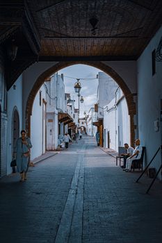 Serene narrow alleyway with arches and people, capturing a peaceful street scene.