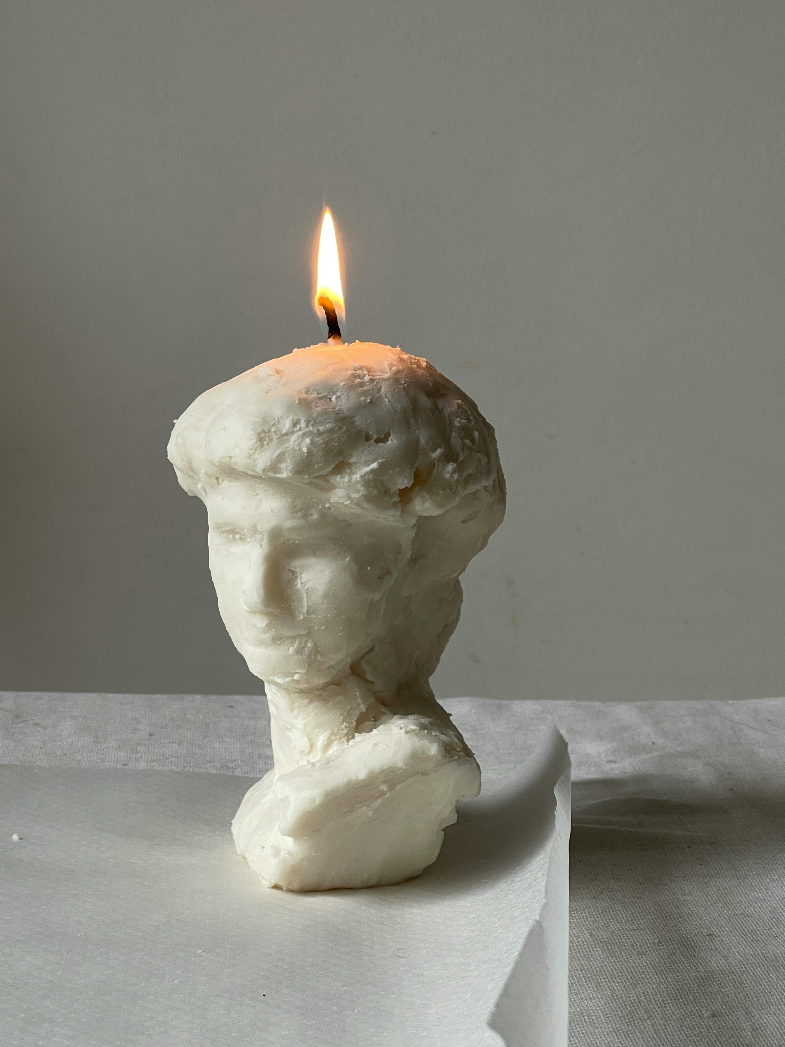 burning candle on wax bust