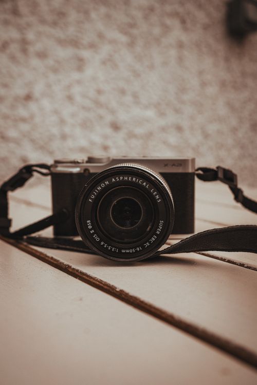 Free Close-up of a vintage camera with a leather strap on a rustic wooden surface. Stock Photo