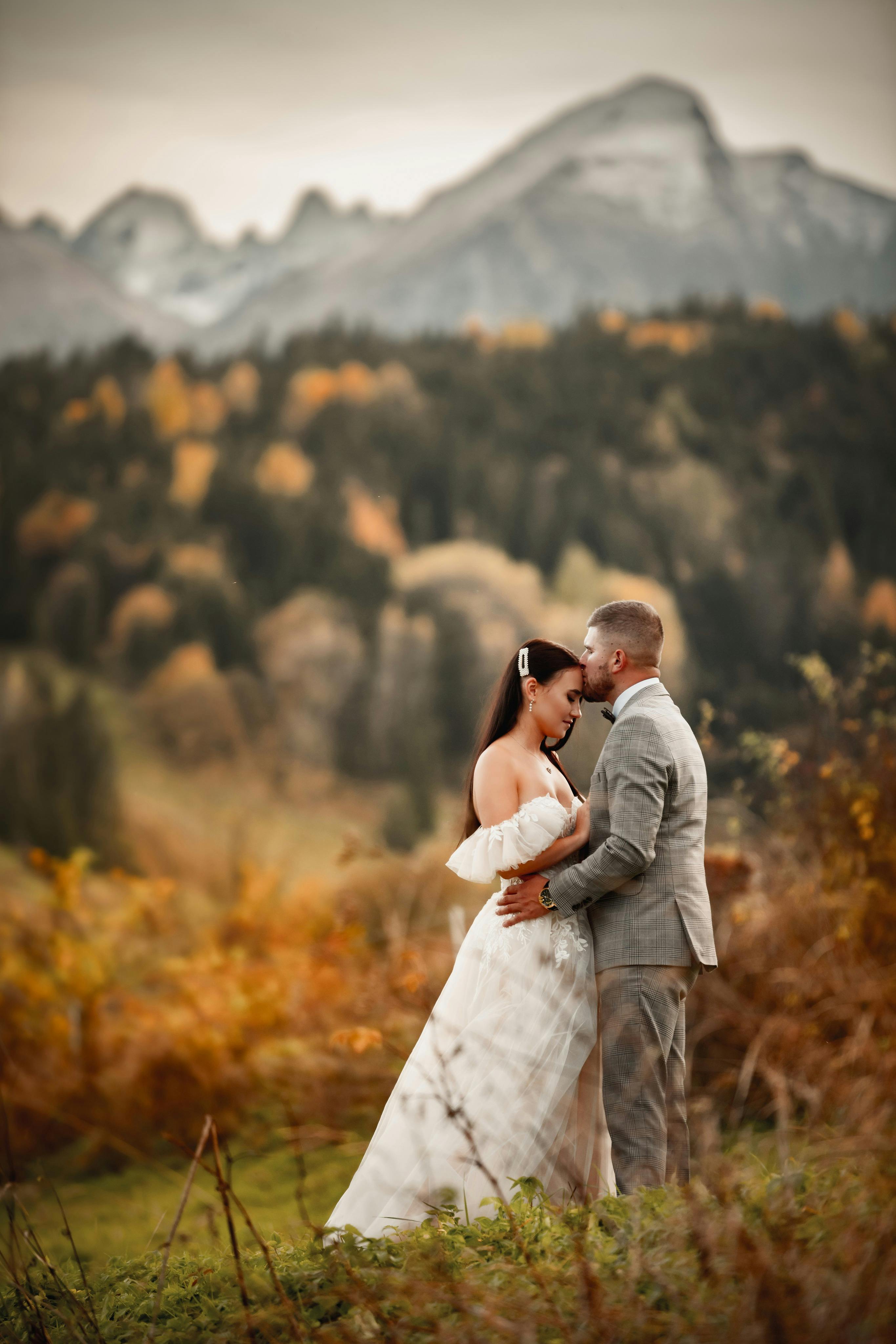 A romantic portrait of newlyweds embracing in a mountainous autumn landscape.
