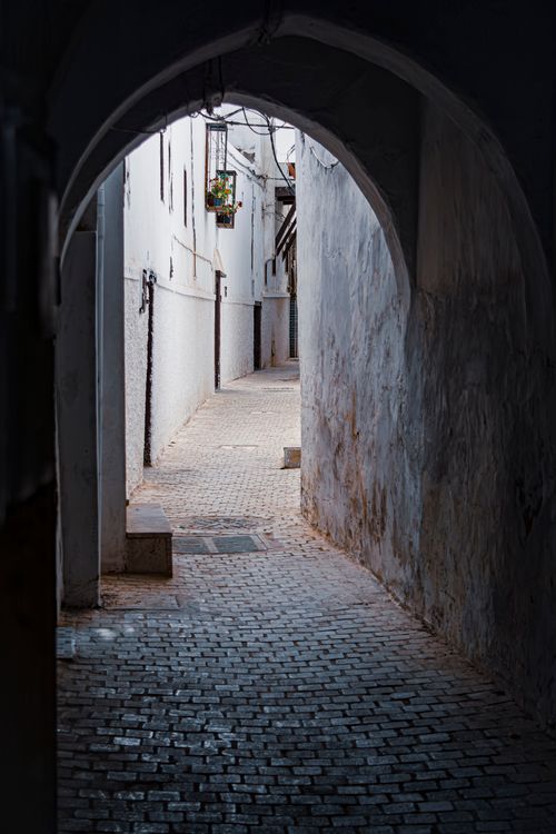 Free Explore the charm of a narrow, cobblestone alley in a historic town, framed by archways. Stock Photo