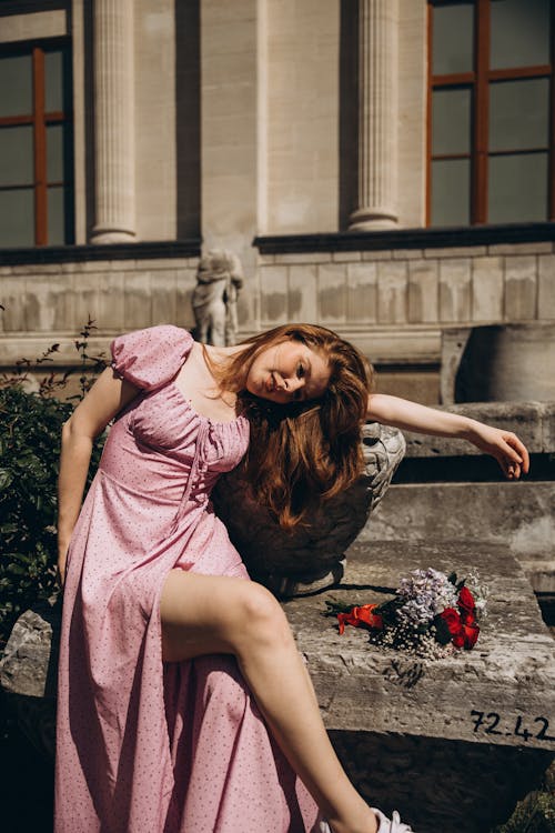 A woman in a pink dress laying on a stone