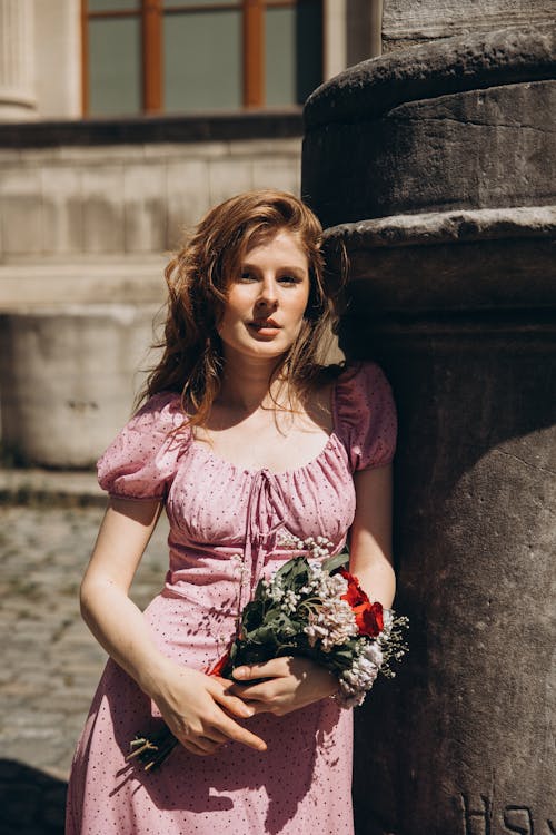 A woman in a pink dress holding a bouquet of flowers