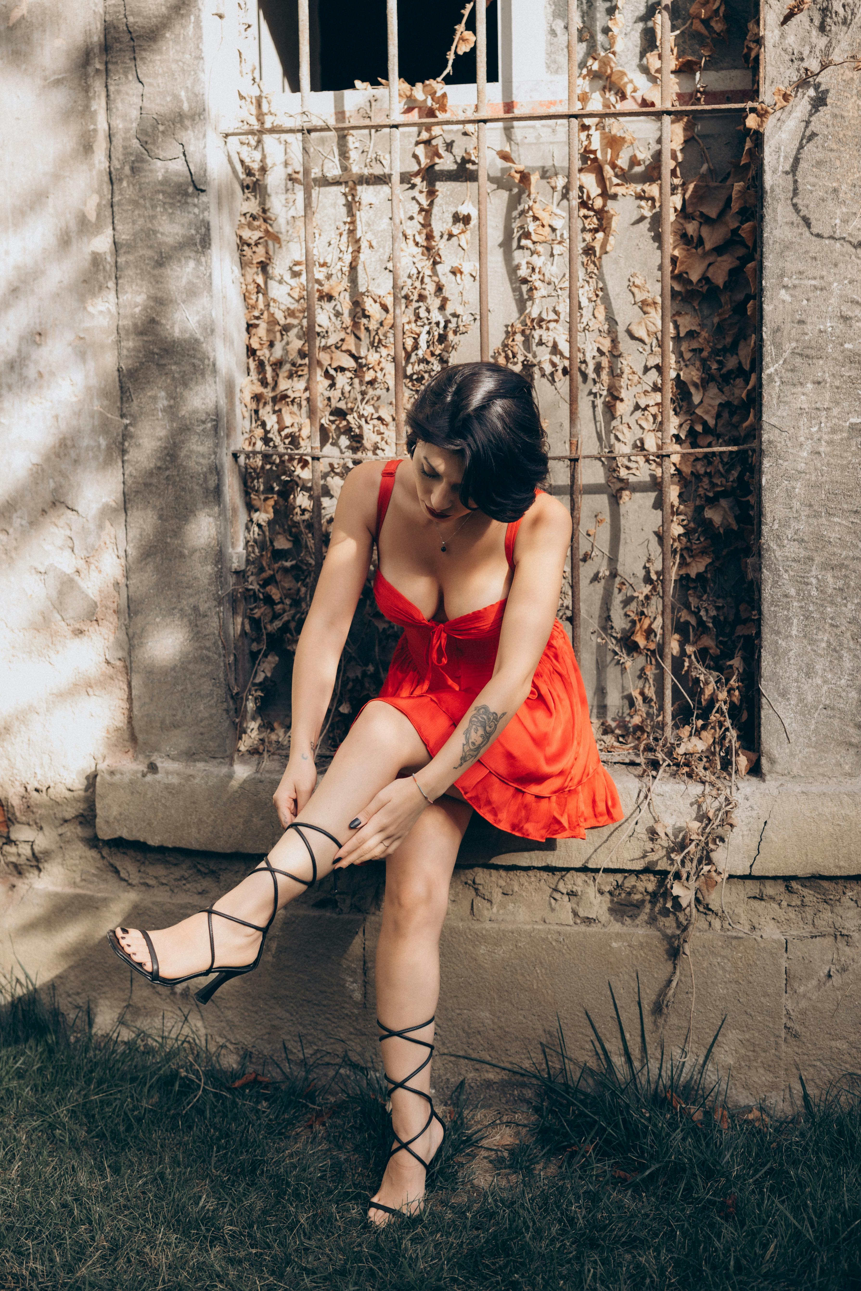 a woman in red dress sitting on a wall