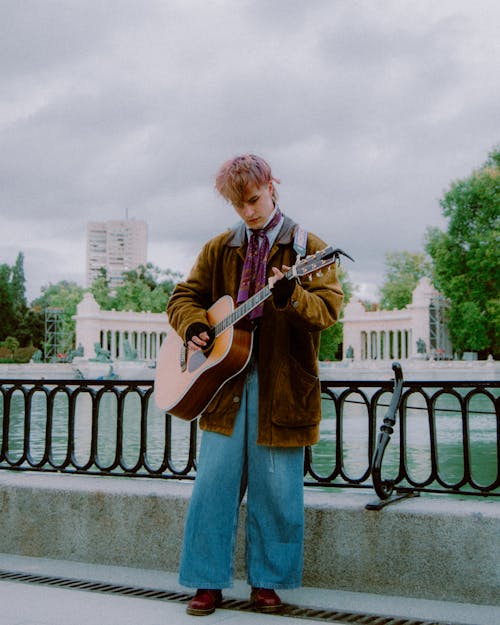Man with Dyed Hair and with Guitar in Park