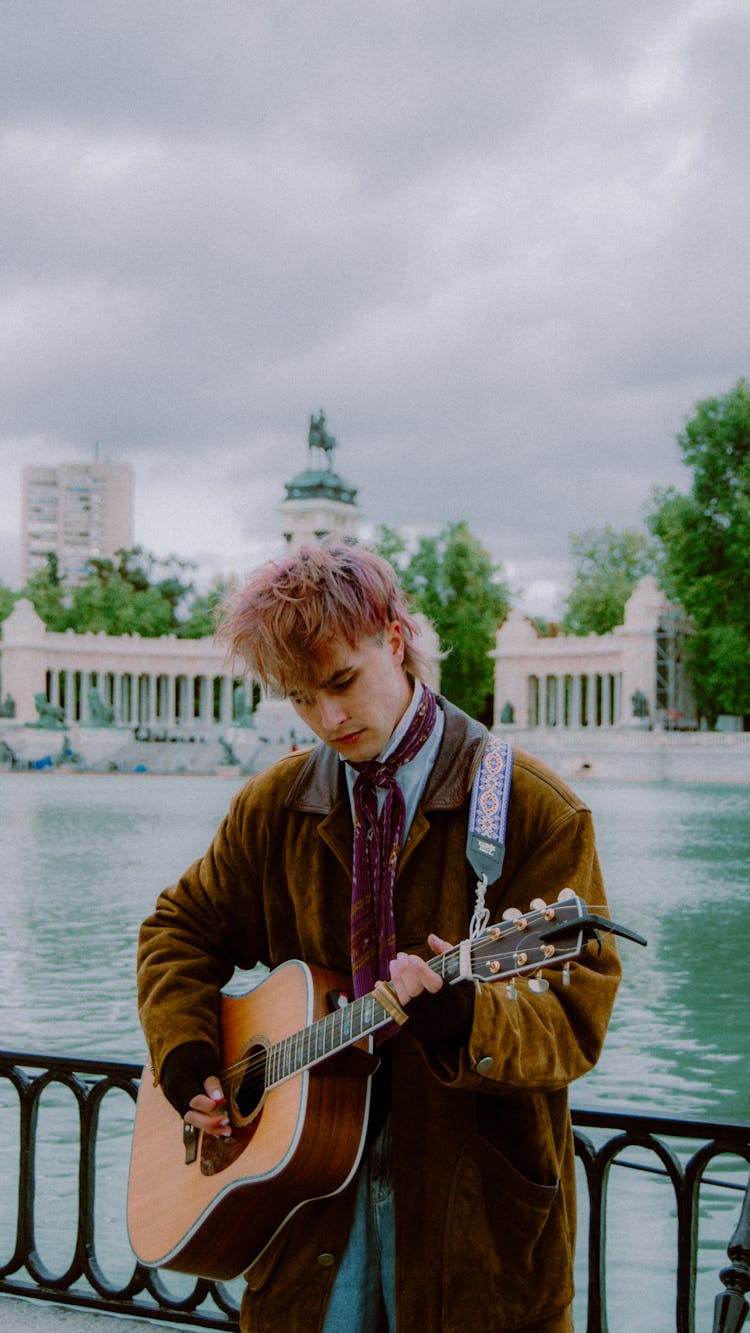 Young Man With Dyed Hair Playing Guitar On The Promenade