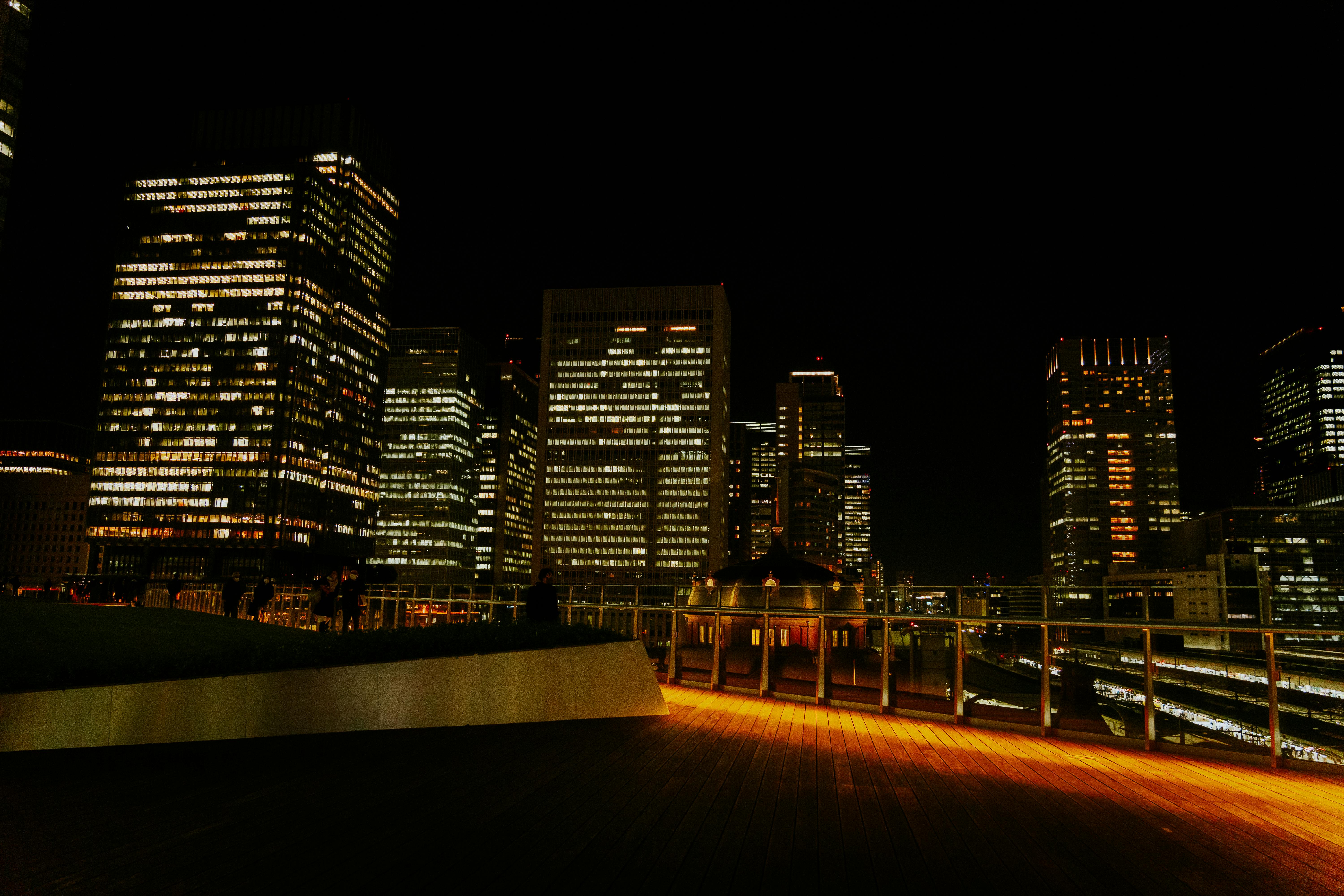 Beautiful night view of Tokyo skyscrapers with illuminated buildings and reflections on a railing.
