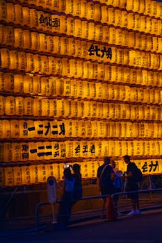People enjoying a vibrant display of traditional Japanese lanterns in Tokyo at night.