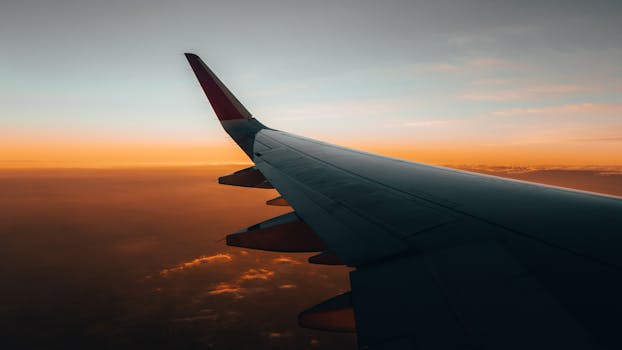 Stunning view of an airplane wing soaring above clouds during a vibrant sunrise.