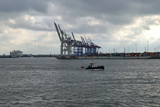 A busy industrial harbor with cranes and a boat under dramatic cloudy skies.