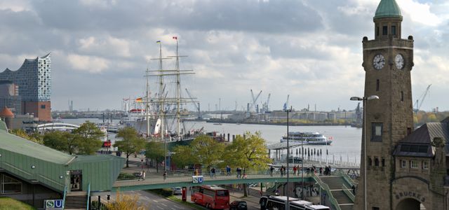 A busy day at Hamburg's harbor featuring the Elbphilharmonie, historic ships, and clock tower.