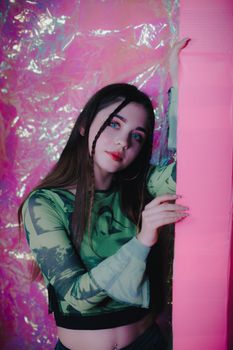 Portrait of a young woman in a green top against a pink artistic background.