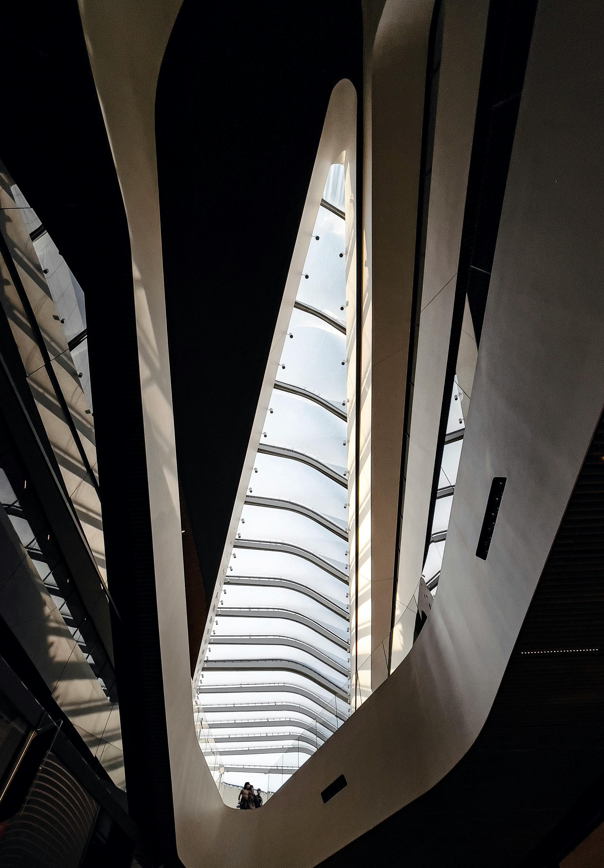 A low angle view of modern architecture with a sleek glass roof and futuristic design.