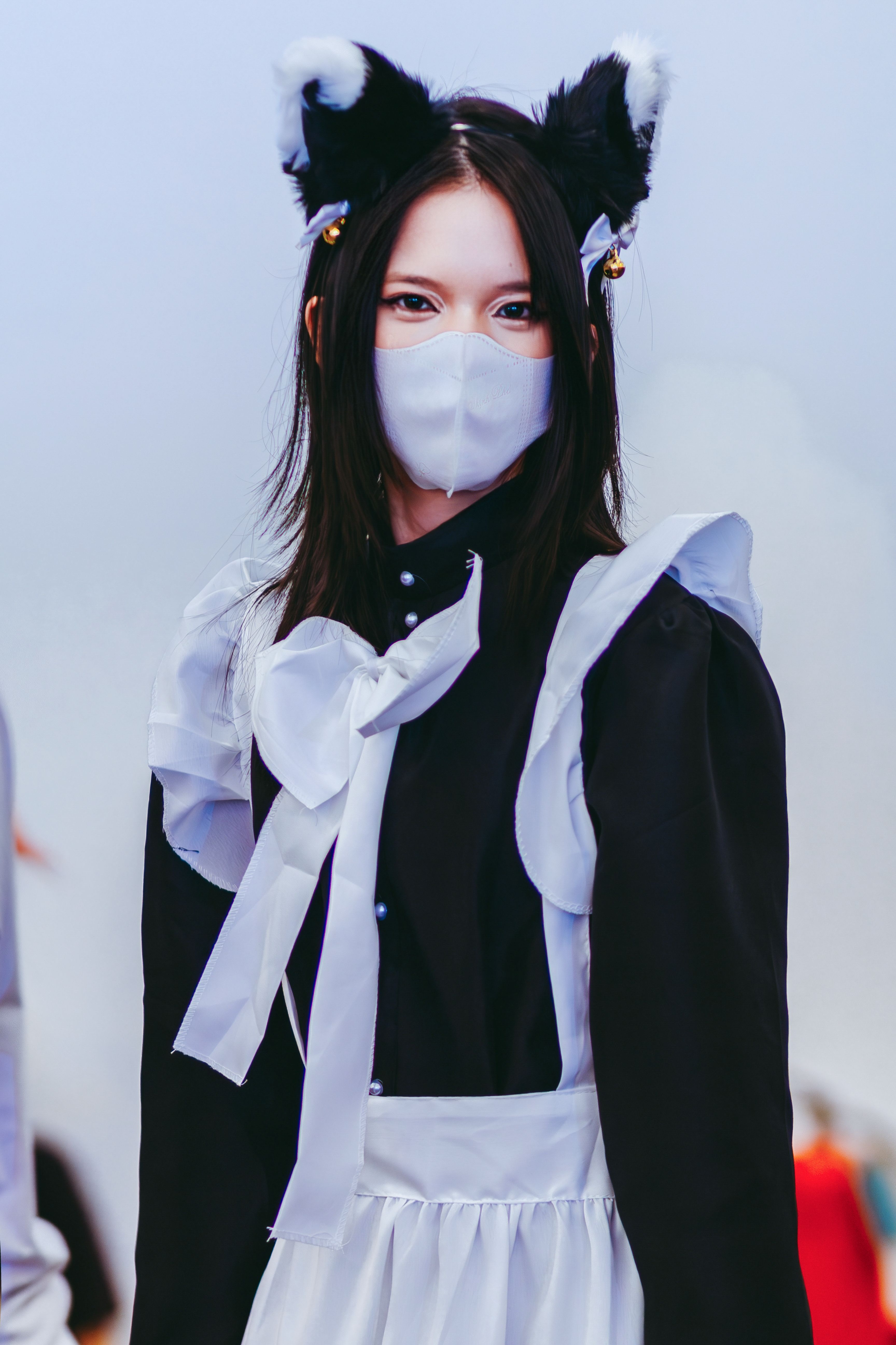 Portrait of a woman in anime-style cosplay with mask and cat ears.