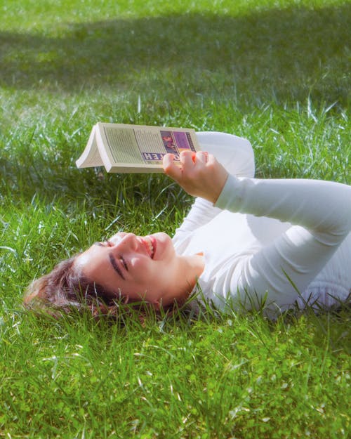 Free Woman Lying on Grass with Book Stock Photo