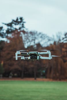 Close-up view of a drone mid-flight in a park with autumn foliage.