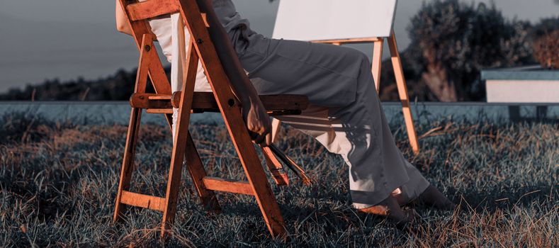 Artist sitting outdoors in Vlorë, Albania, with an easel at sunset, creating art in a serene setting.