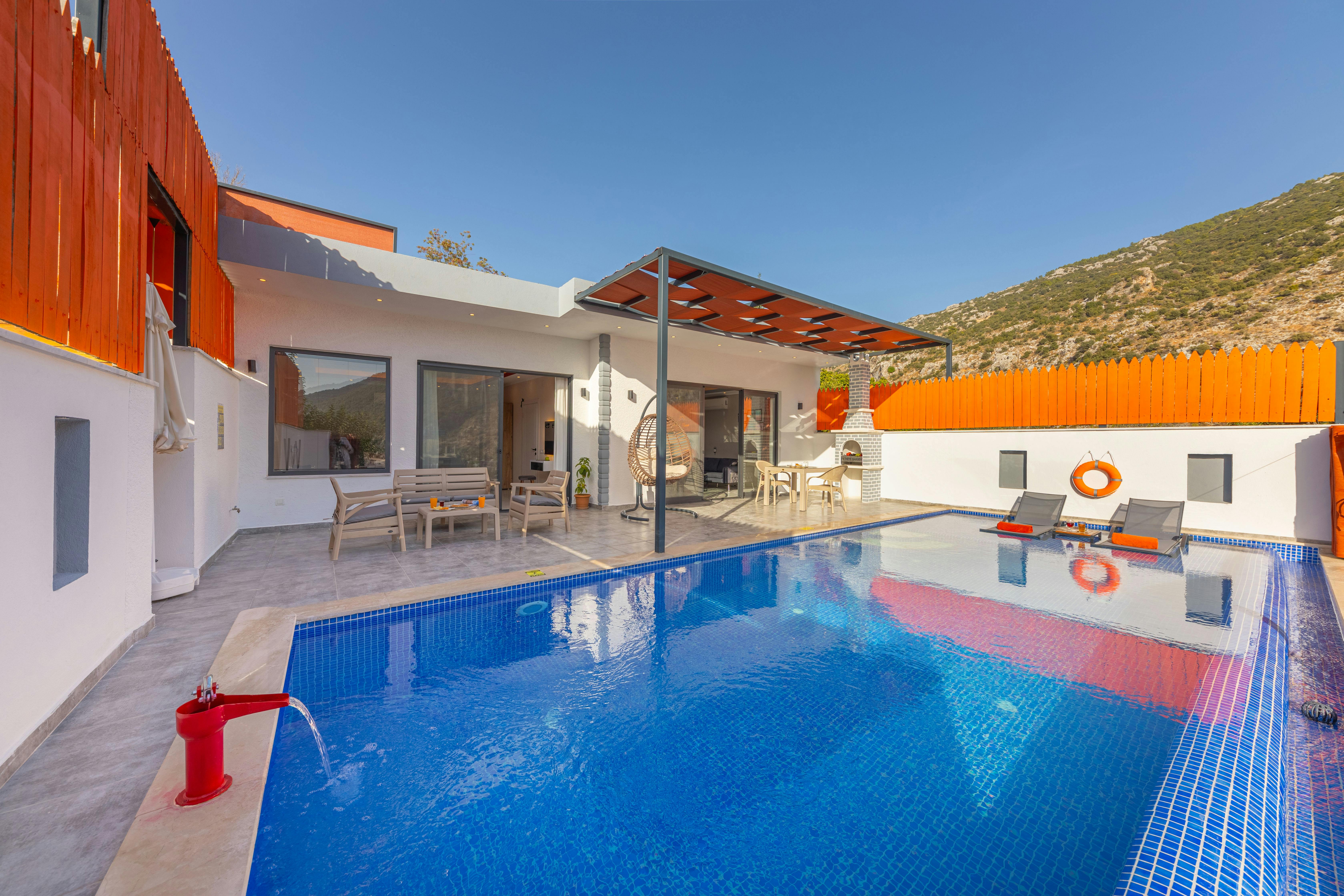 Bright outdoor pool area at a modern home with a patio, perfect for relaxation.